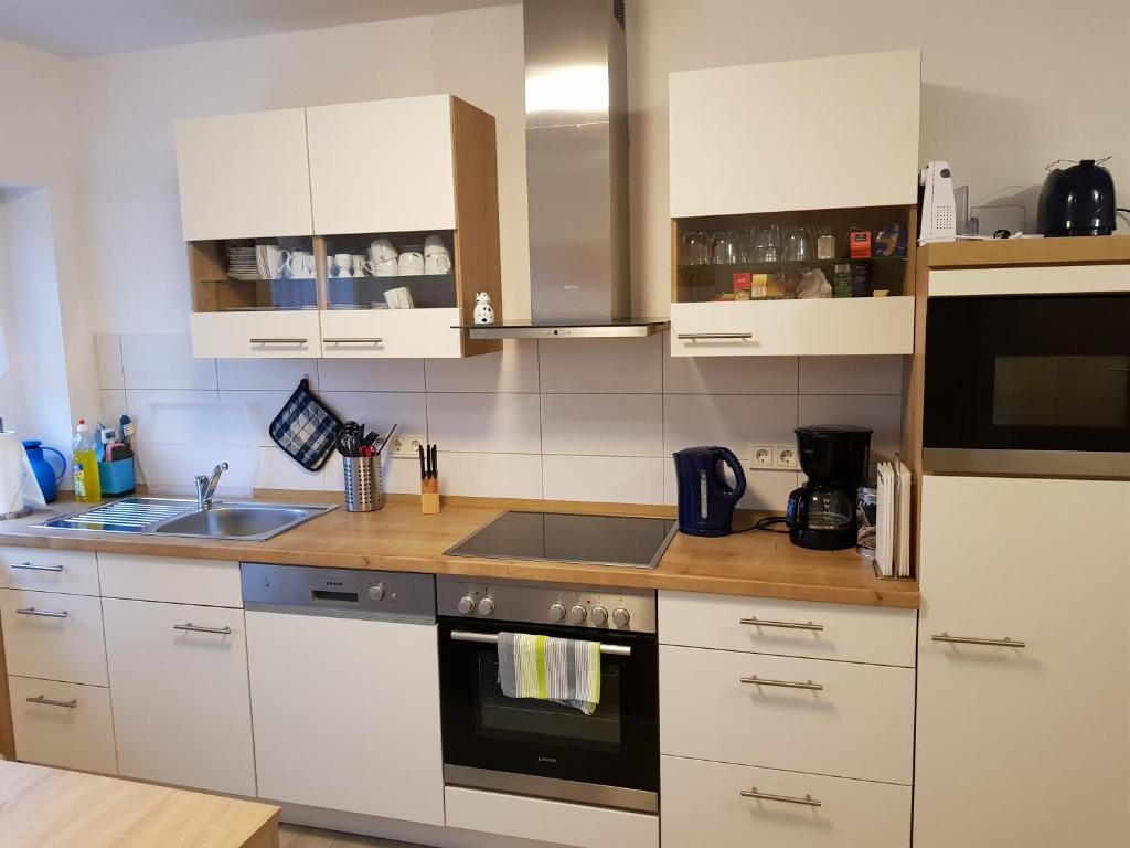 eine Küche mit weißen Schränken und einem Herd mit Backofen in der Unterkunft DA Ferienwohnungen in Bargischow