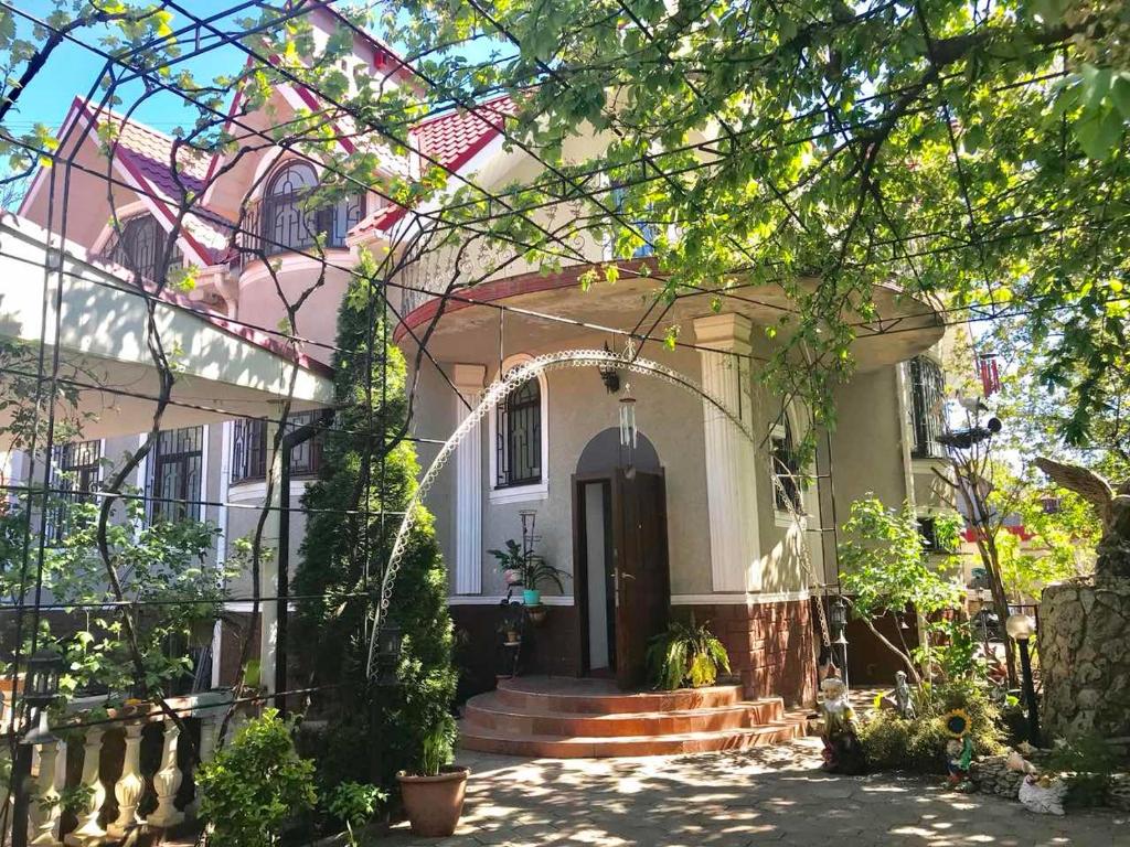 une maison blanche avec une porte noire et des arbres dans l'établissement Lorena, à Odessa