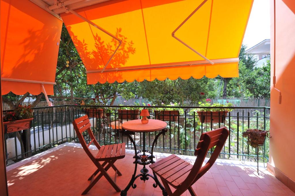 una mesa y sillas bajo una sombrilla en el balcón en Estate4Home - Orange Dreams en Sant'Agnello