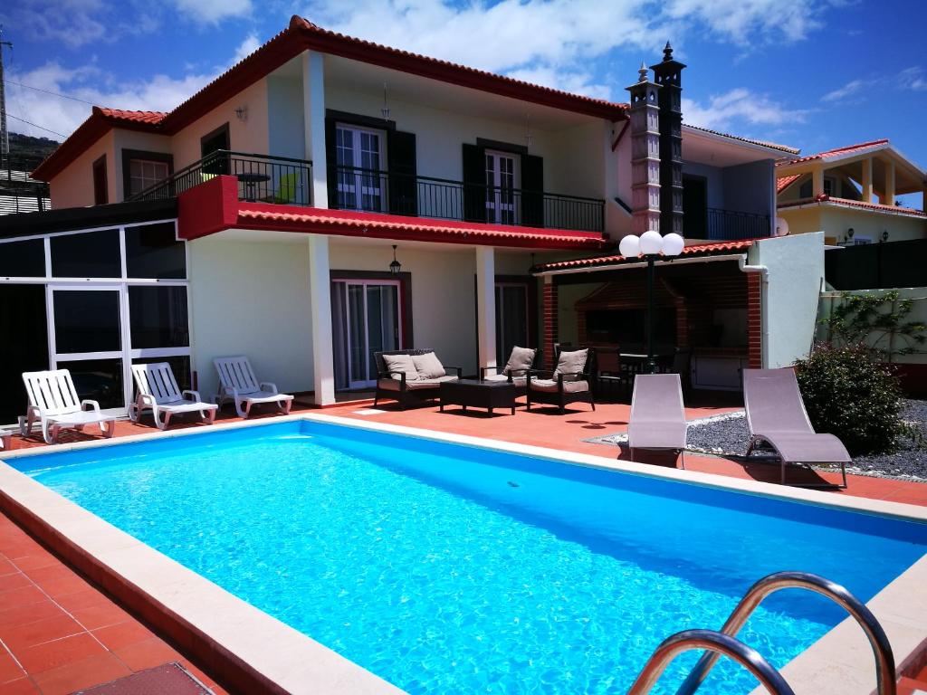 a villa with a swimming pool in front of a house at Casa Maresia in Ponta do Sol