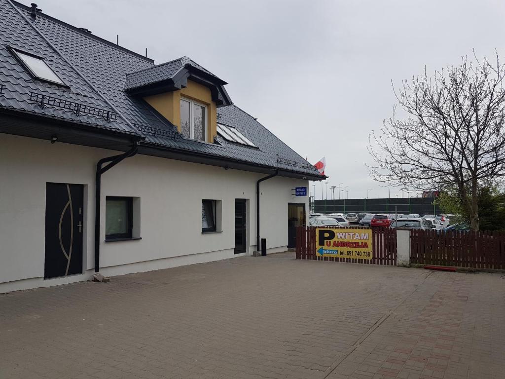 a white building with a fence next to a parking lot at Noclegi u Andrzeja in Gdańsk