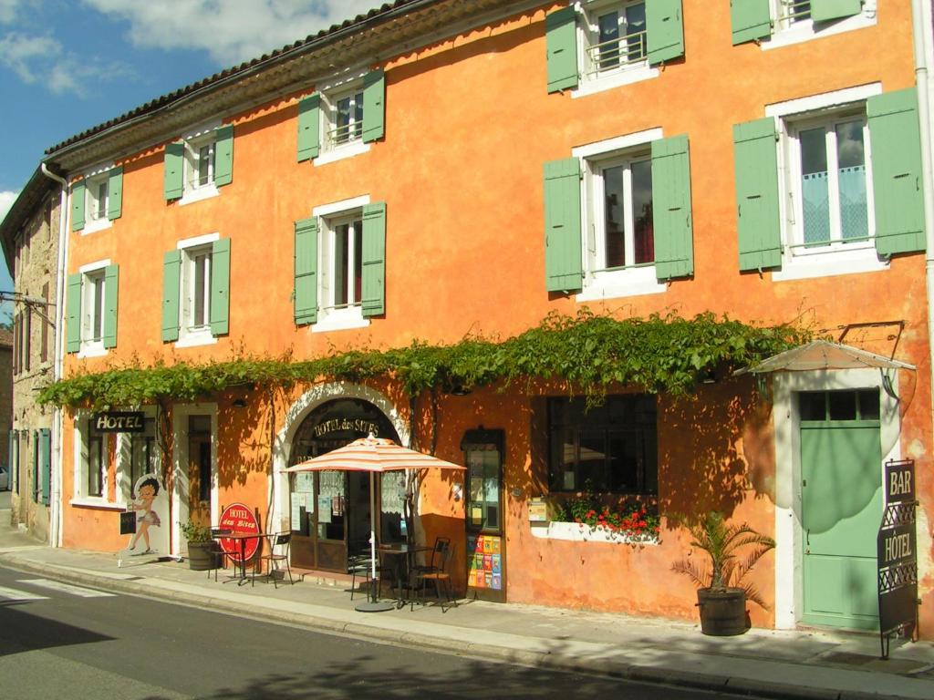 ein orangefarbenes Gebäude mit einem Regenschirm auf einer Stadtstraße in der Unterkunft Hotel Des Sites in Salavas