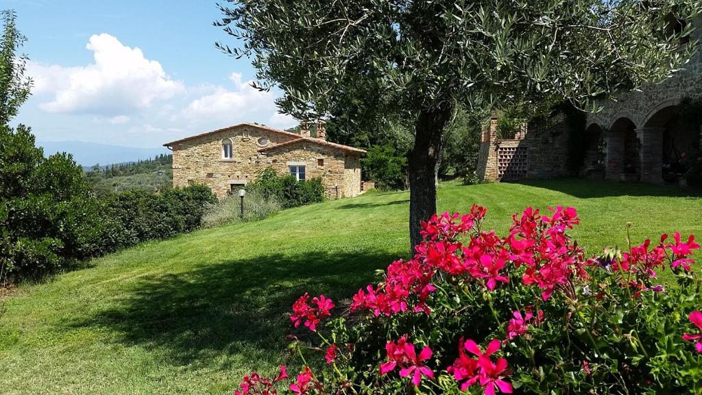 a stone house on a hill with pink flowers at Antica Dimora in Rigutino