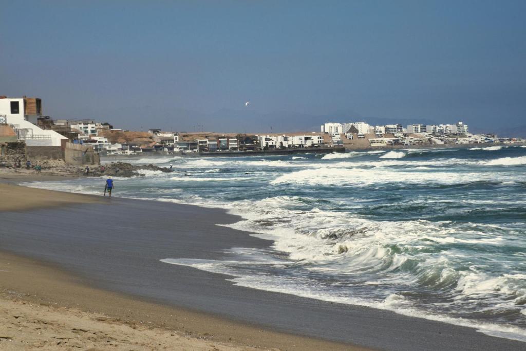 una persona parada en la playa cerca del océano en Casa de Playa Arica, en Lurín