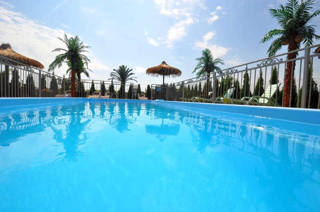 a large blue swimming pool with palm trees and a fence at Willa Ciskowscy in Władysławowo