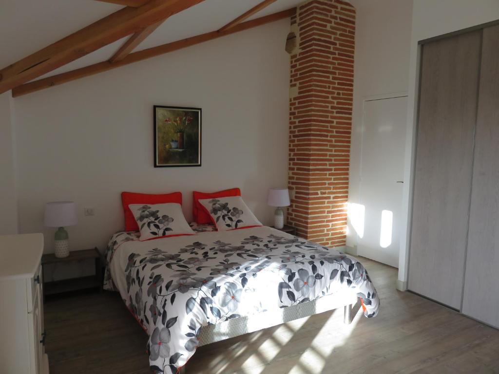 a bedroom with a bed and a brick wall at Chambres d'Hôtes Lieu Dit Cruzel in Moissac