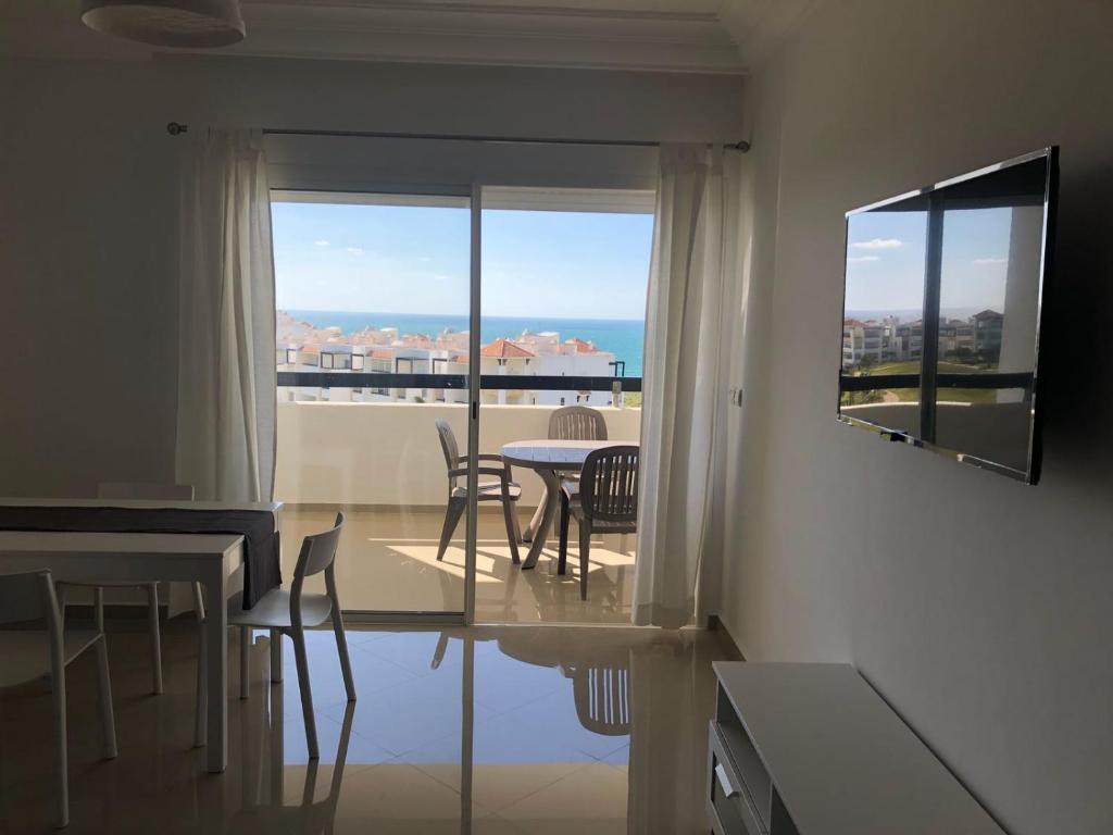 a living room with a table and chairs and a window at Marina Golf Appart Chez Hicham in Asilah