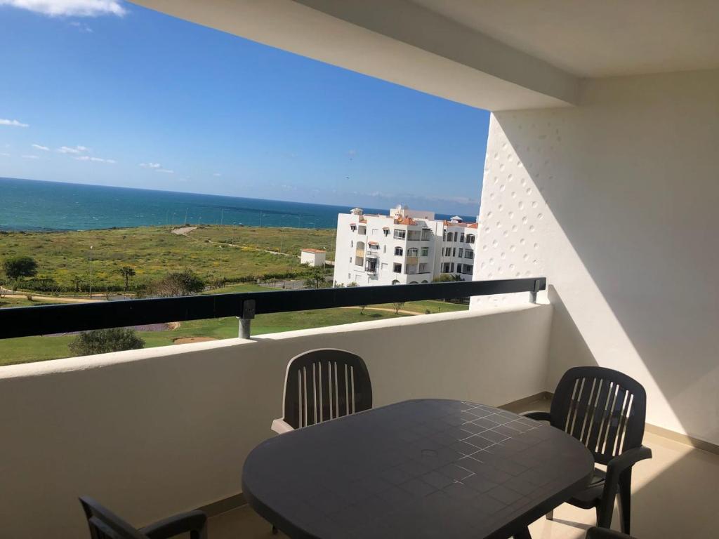 a table and chairs on a balcony with a view of the ocean at Marina Golf Appart Chez Hicham in Asilah