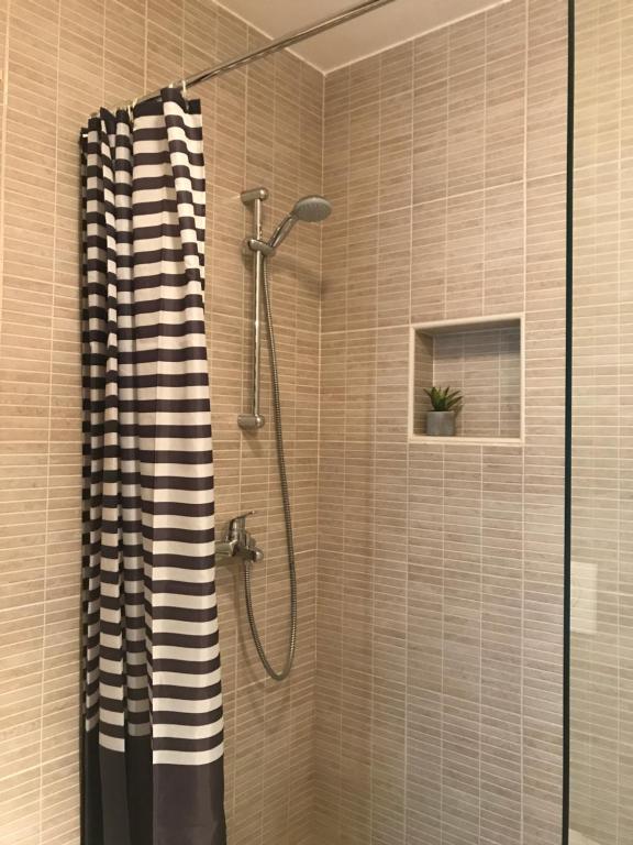 a shower with a black and white shower curtain in a bathroom at Apartment Adi in Travnik