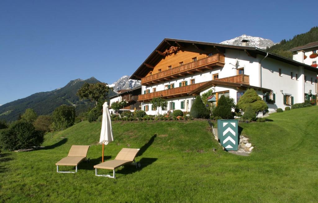 una casa en una colina con dos sillas y una sombrilla en Landgut Thalerhof, en Telfes im Stubai