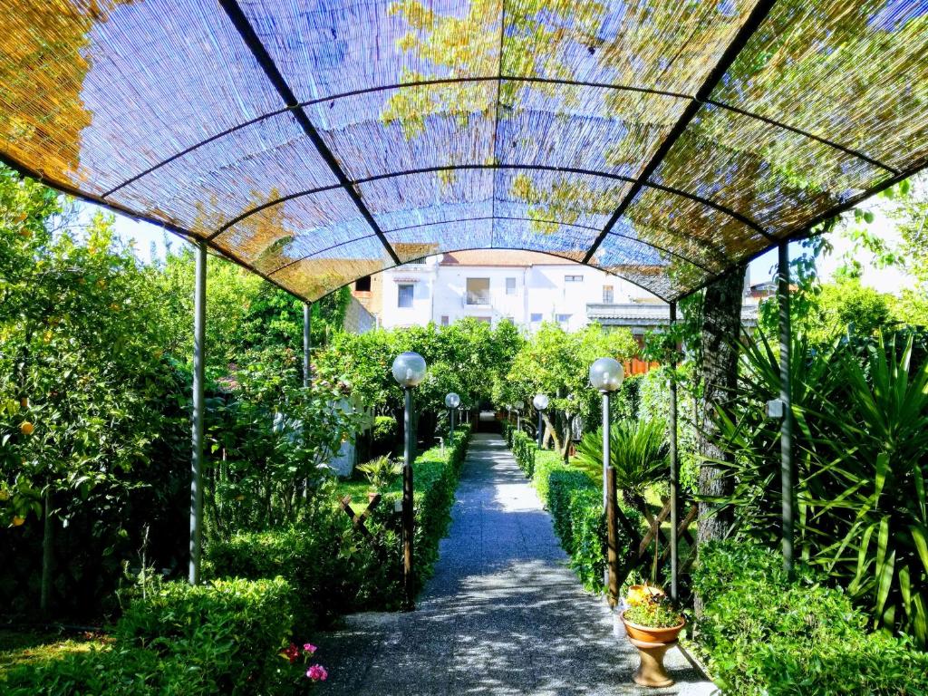 Residenza Caserta Sud - Appartamento con giardino في كازيرتا: ممشى من خلال حديقة ذات سقف زجاجي