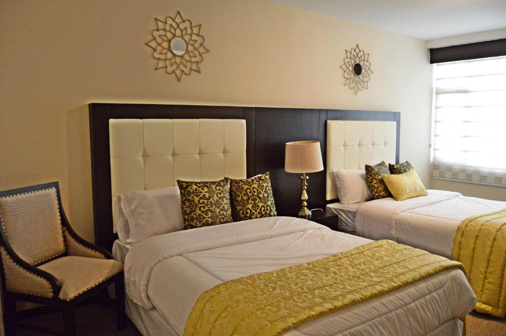 1 dormitorio con 2 camas y 1 silla en Hotel Golosone, en Ambato