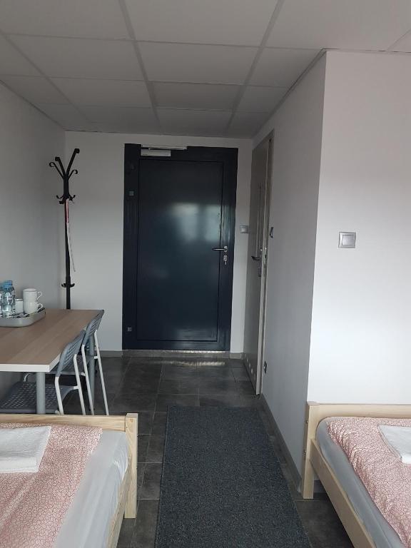 a room with two beds and a table and a door at Noclegi u Andrzeja in Gdańsk