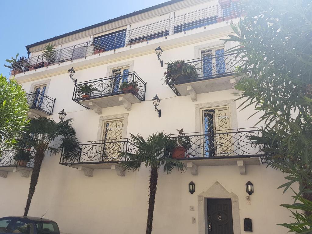 a white building with balconies and palm trees at Rodeo Drive in Viareggio