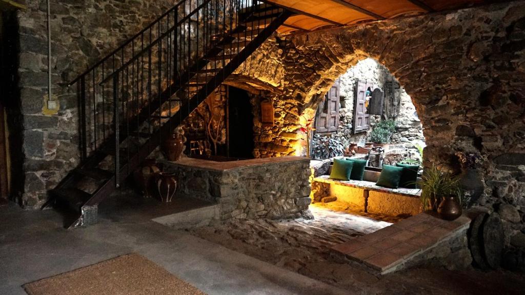 Casa de piedra con escalera y sofá en Mas Gibert, en Sant Gregori