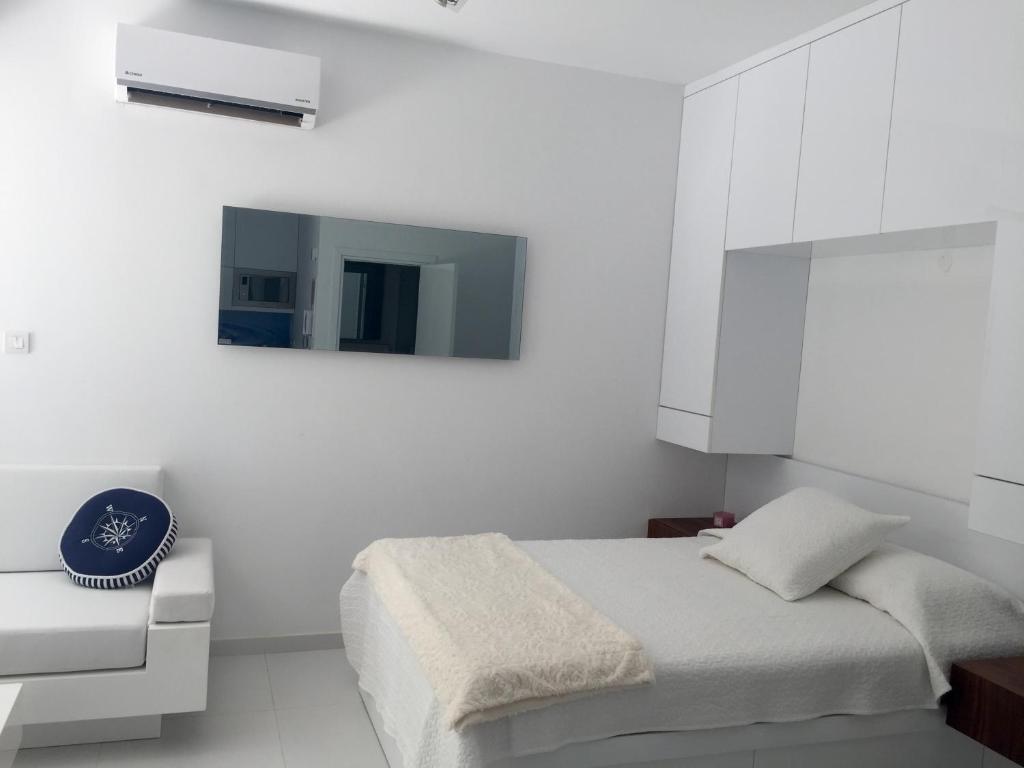 a white bedroom with a bed and a tv at Modern Seaview Beach Studio Limassol in Limassol