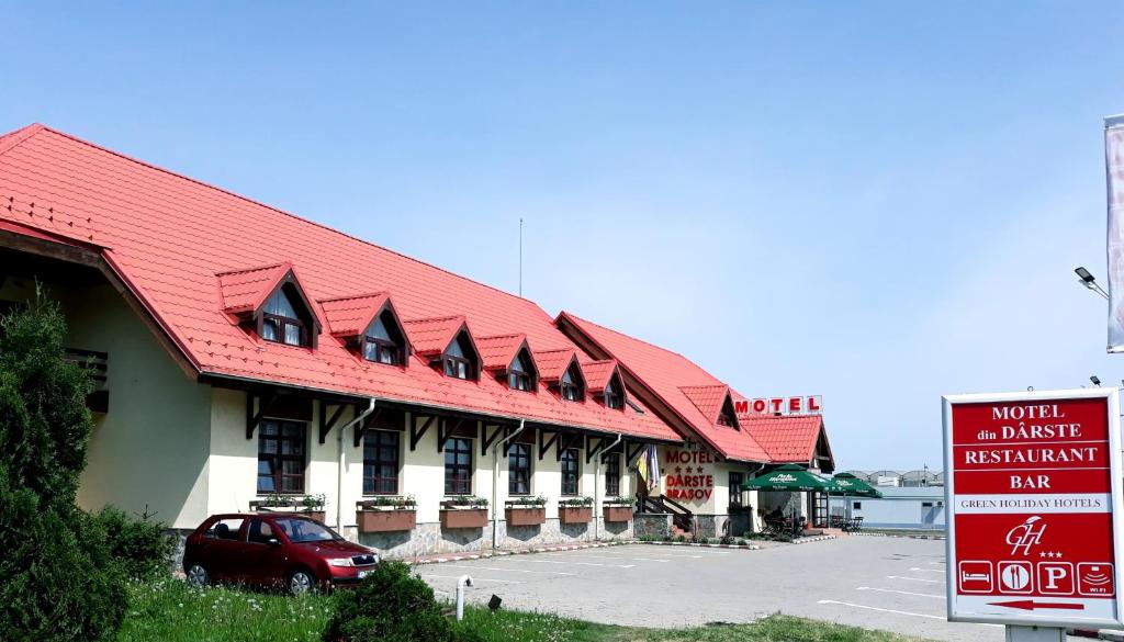 un edificio con techo rojo junto a un aparcamiento en Motel din Darste, en Săcele