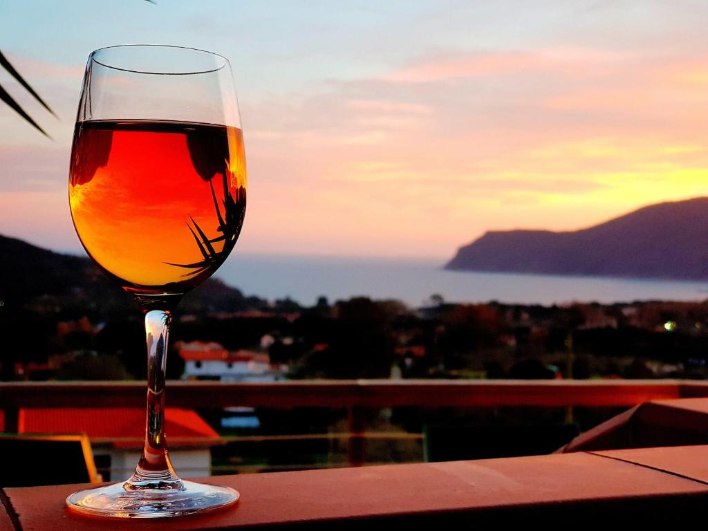 Mini Appartamenti Elba في لاكونا: وجود كأس من النبيذ على طاولة مع غروب الشمس
