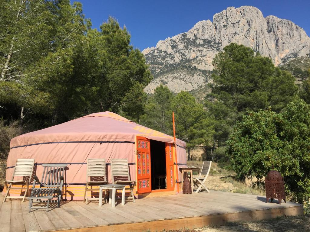 an orange yurt with chairs and tables and a mountain at La Yurta Naranja in Finestrat