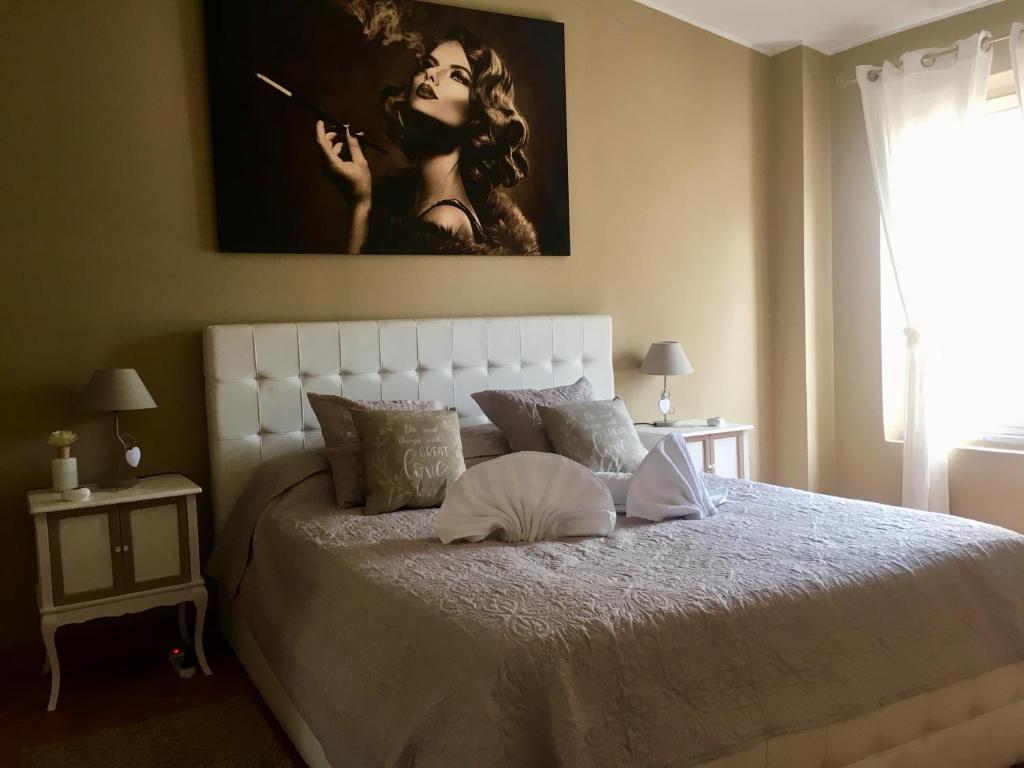 a bedroom with a white bed with a picture on the wall at Chic 'N Charme Trastevere Terrace in Rome