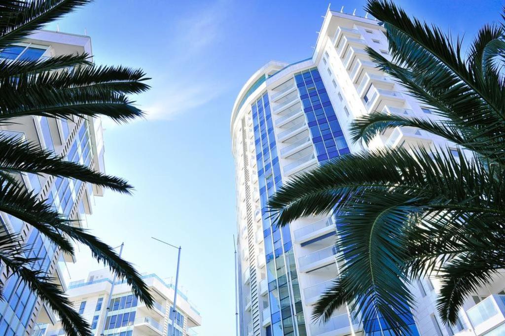 a tall building with palm trees in front of it at Apartments Menuet in Budva
