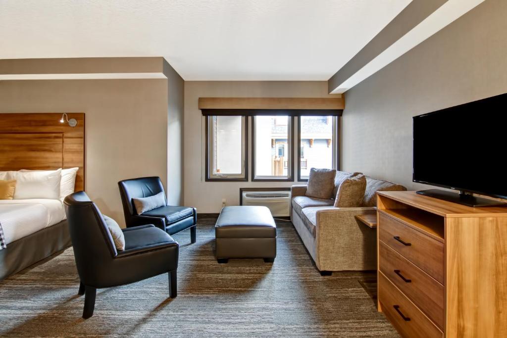 a hotel room with a bed and a flat screen tv at Canalta Lodge in Banff