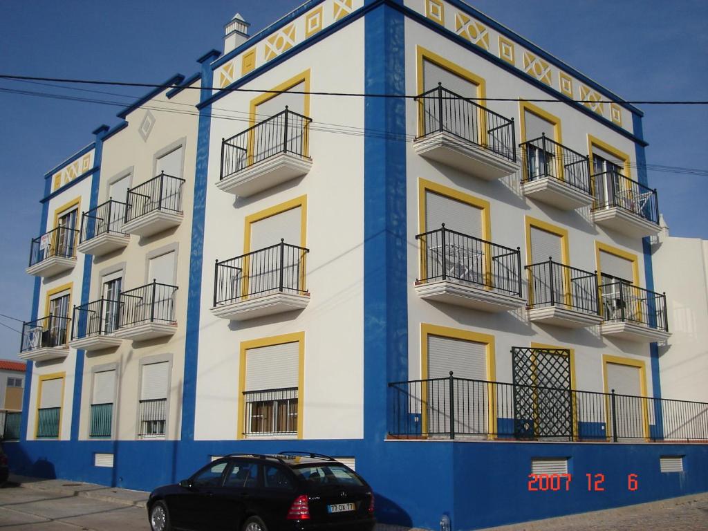 un edificio azul y blanco con un coche aparcado delante en Alagoa Azul II en Altura