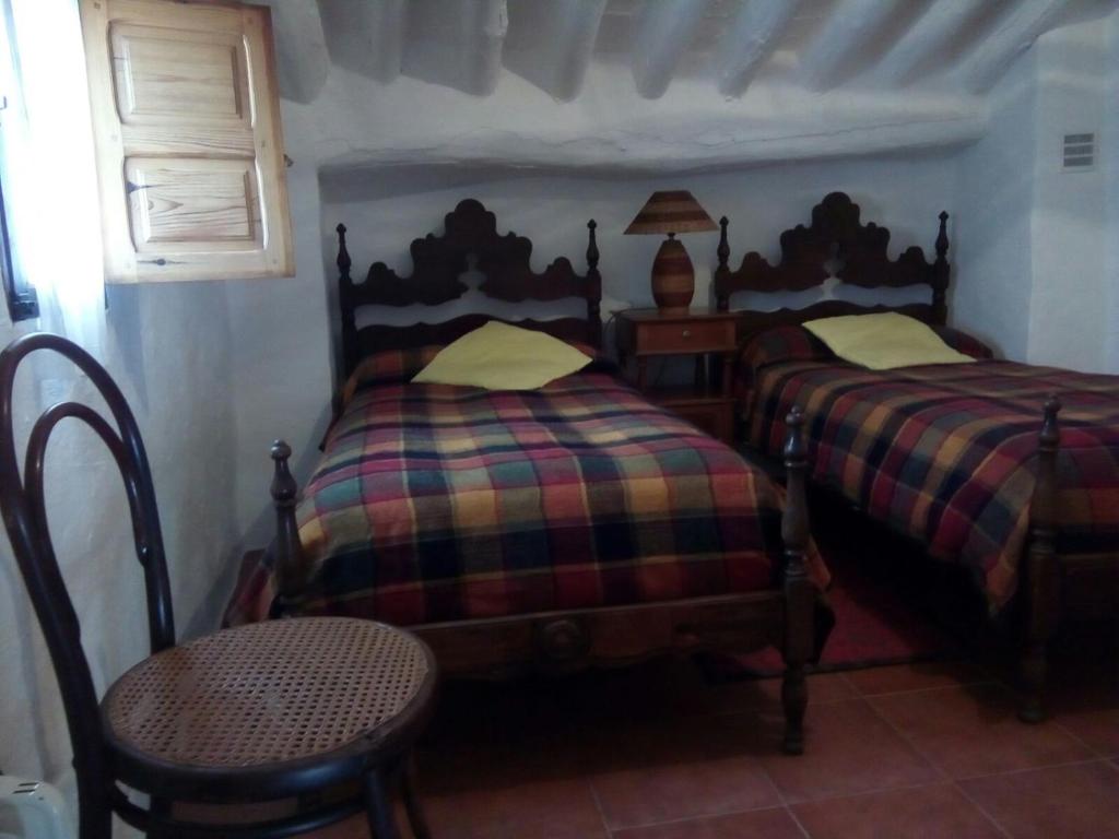 a bedroom with two twin beds and a chair at Las Parras in Rute