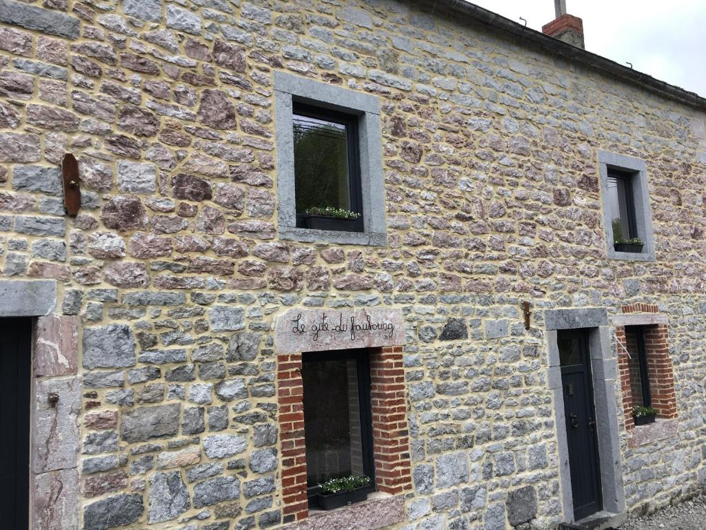 un antiguo edificio de piedra con tres ventanas. en Le gîte du faubourg, en Sautour