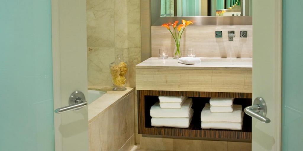 a bathroom with a sink and a shower with towels at L'Hermitage Hotel in Vancouver