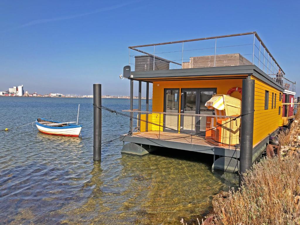 una casa gialla sull'acqua con una barca di Ostsee Hausboot Swantje a Heiligenhafen