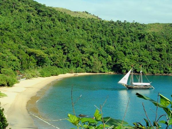 a boat in the water next to a beach at Green House Jabaquara in Paraty