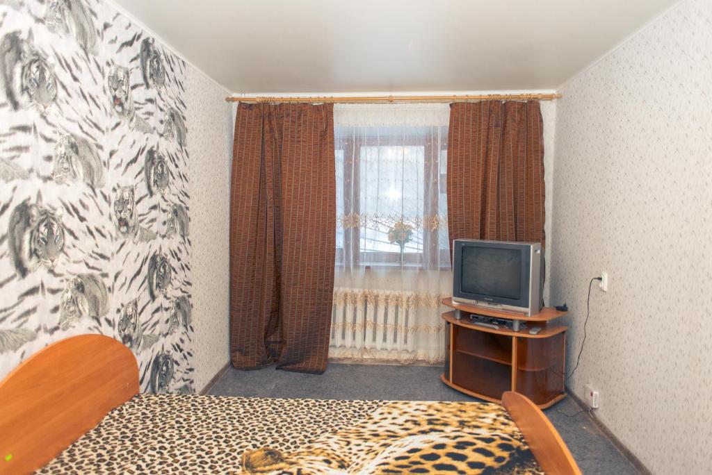 1 dormitorio con 1 cama y mesa con TV en Апартаменты на Курской, en Tyumen