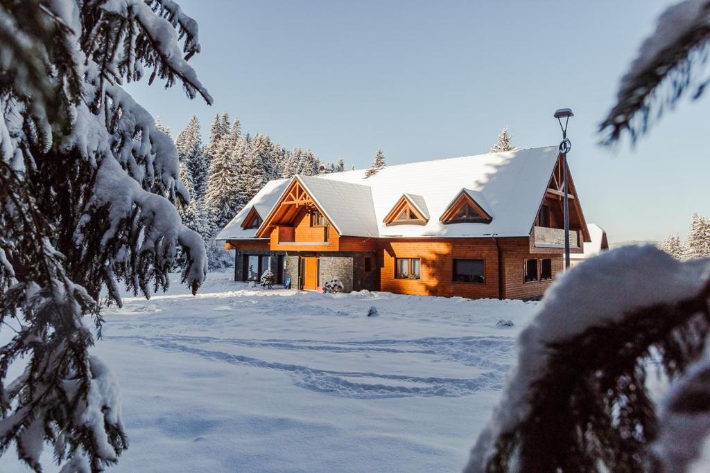 una baita di tronchi nella neve con alberi innevati di Villa Silvia a Zuberec