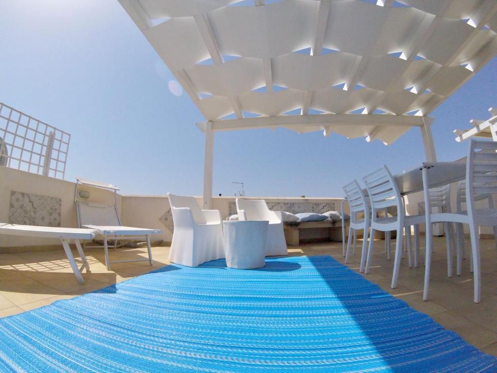 a patio with white chairs and a blue rug at Casa Del Corallo in Favignana