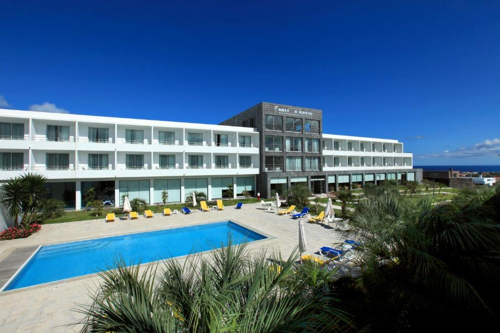 a large blue and white building with a swimming pool in front of it at Hotel Vale Do Navio in Capelas