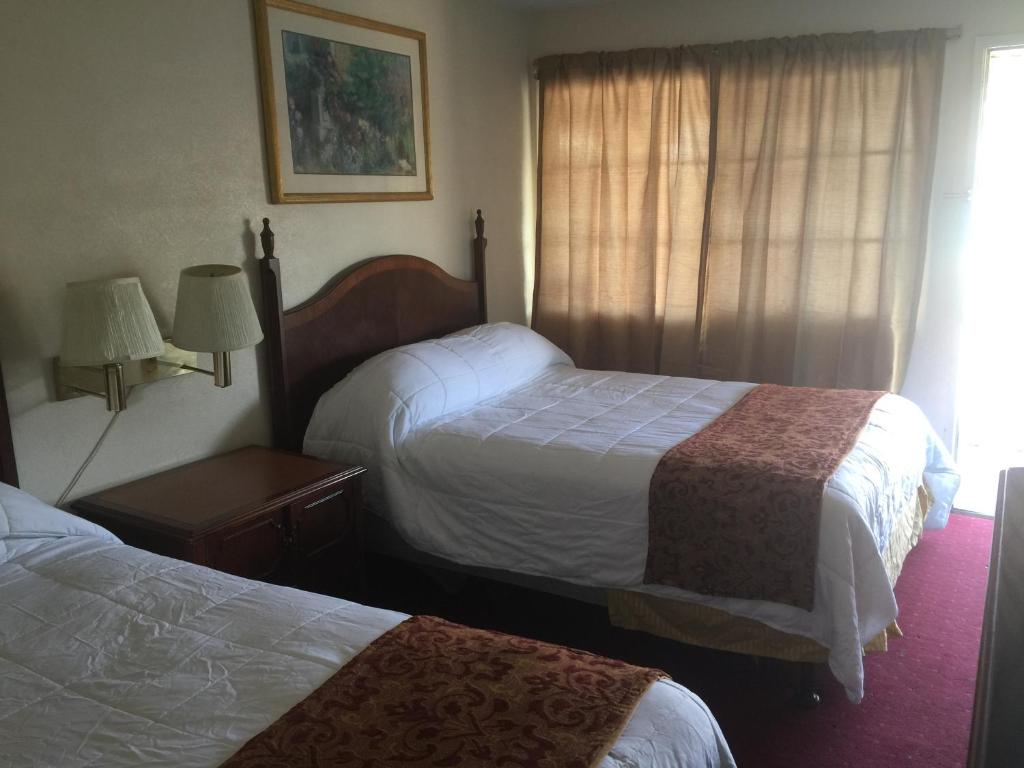 a hotel room with two beds and a window at Frontier Motel in Anaheim