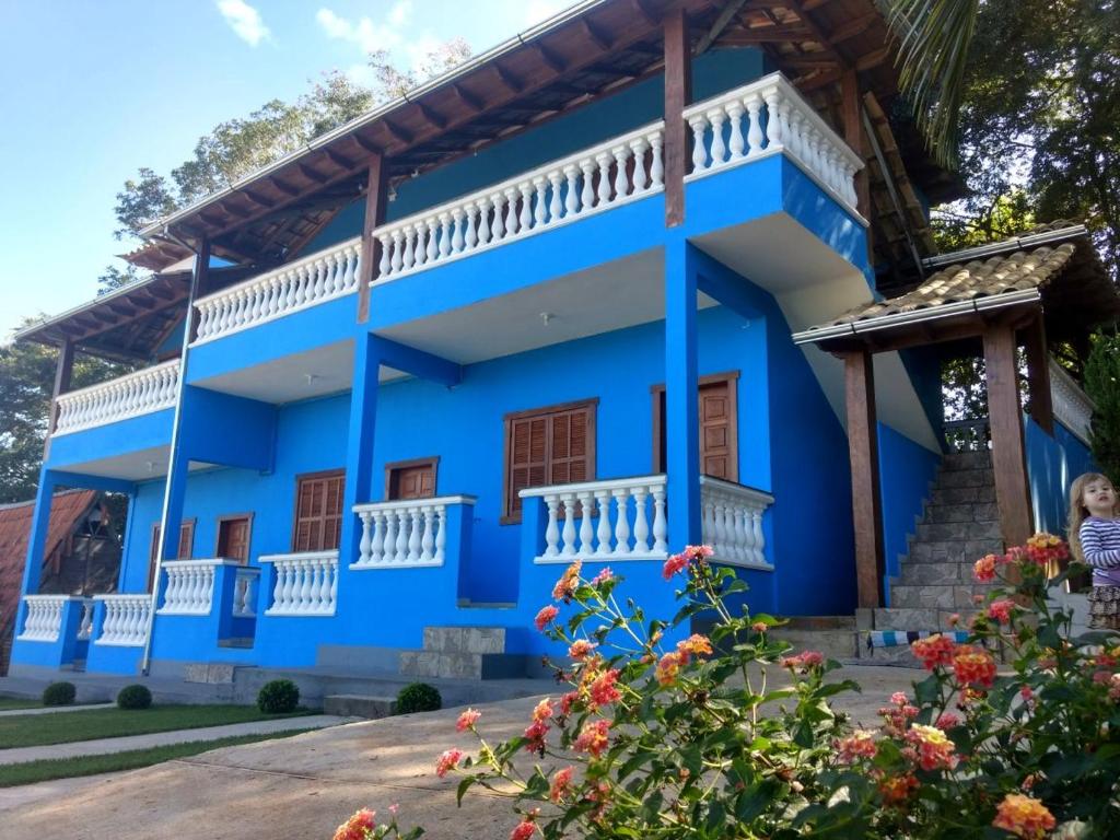 a blue house with white balconies and flowers at Pousada Efraim in Tiradentes