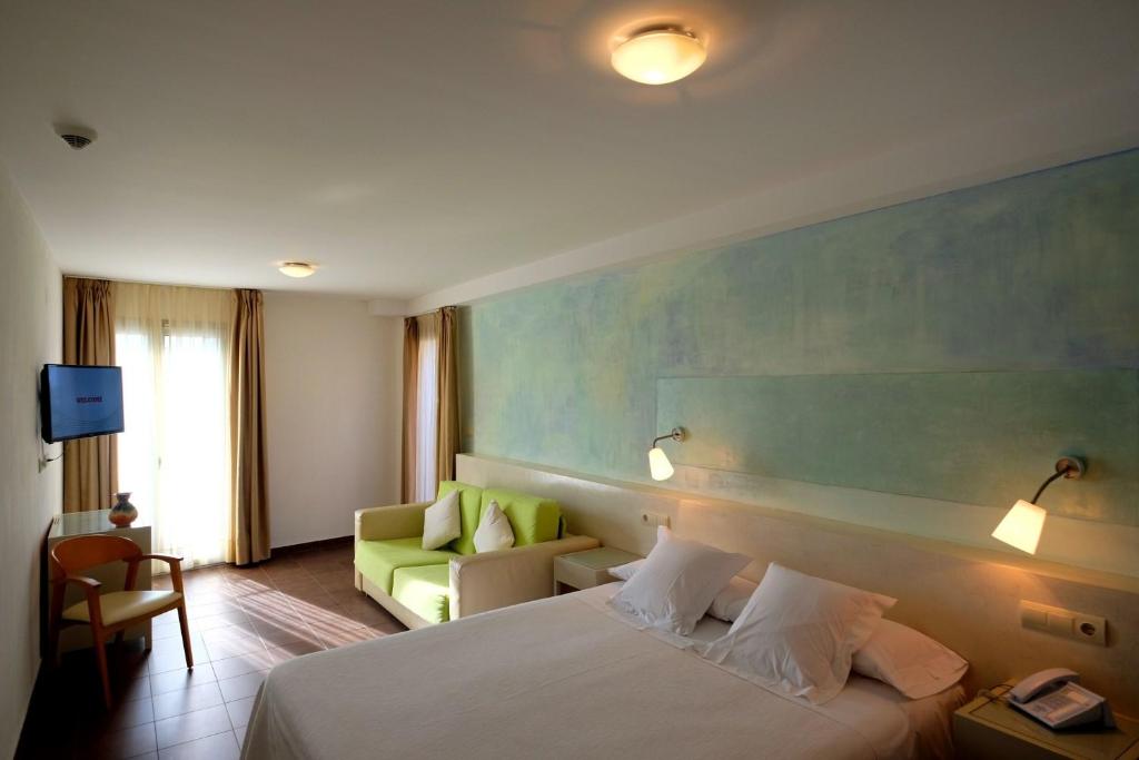 une chambre d'hôtel avec un lit et un canapé dans l'établissement Hotel Carmen, à Roses