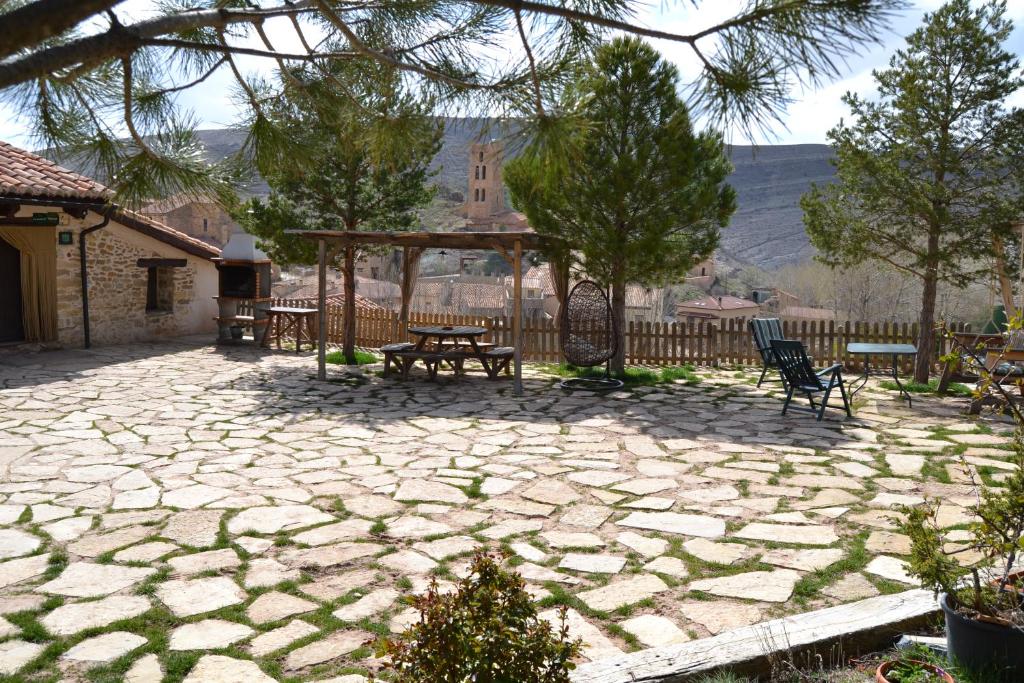 un patio de piedra con bancos y cenador en Casa Elpatiodelmaestrazgo, en Villarroya de los Pinares