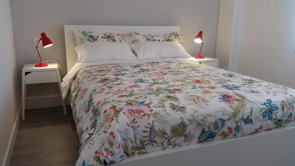 a bedroom with a bed with a floral comforter at AdA Apartamento in Santiago de Compostela