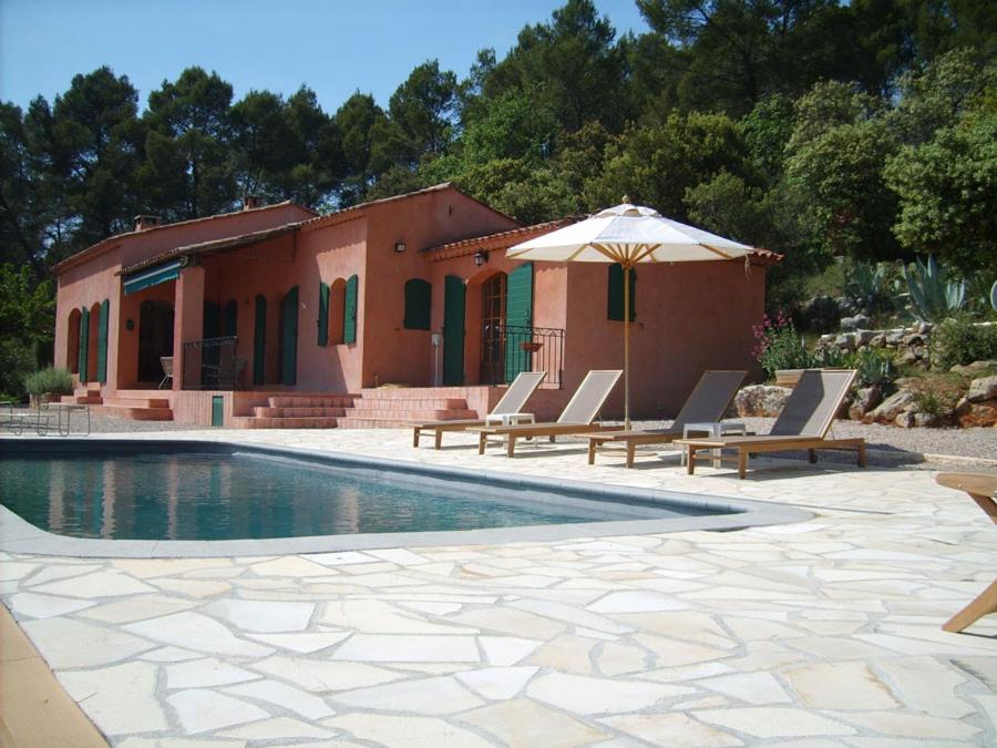 una piscina con sillas y una sombrilla junto a una casa en The Provence Villa, en Entrecasteaux