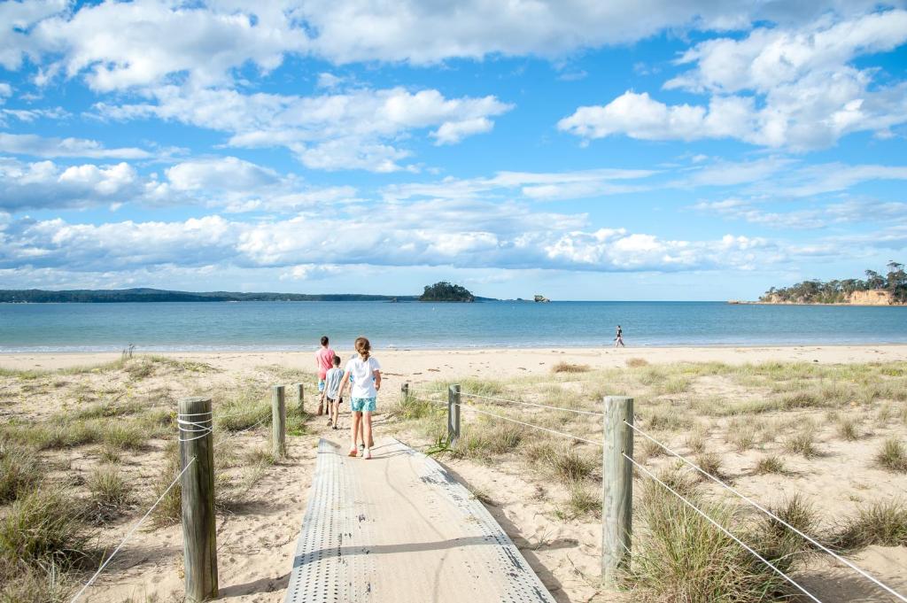 a group of people walking down a boardwalk to the beach at NRMA Batemans Bay Resort in Batemans Bay