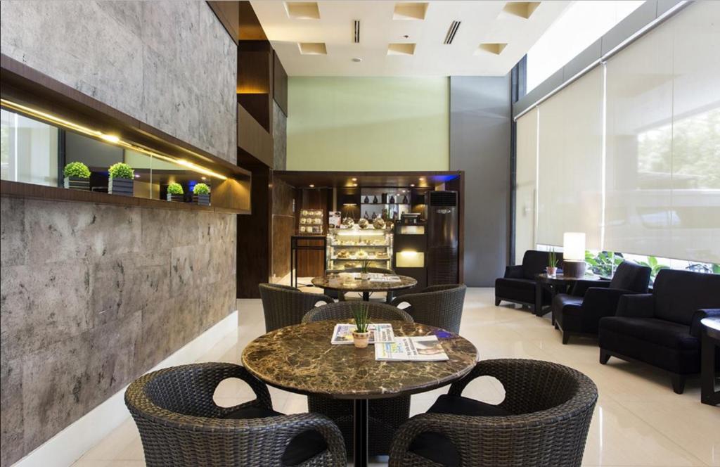 una hall con due tavoli e sedie e un bar di The B Hotel Alabang a Manila