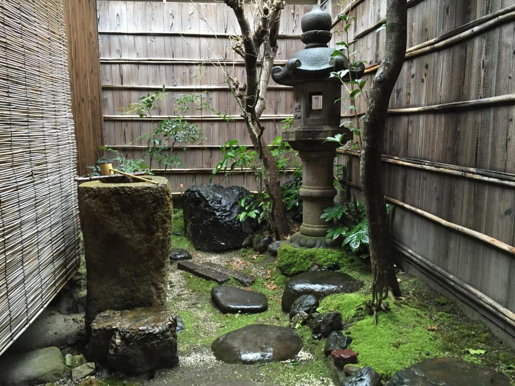 a garden with a bird bath and a fence at Guest House Hitsujian in Kyoto