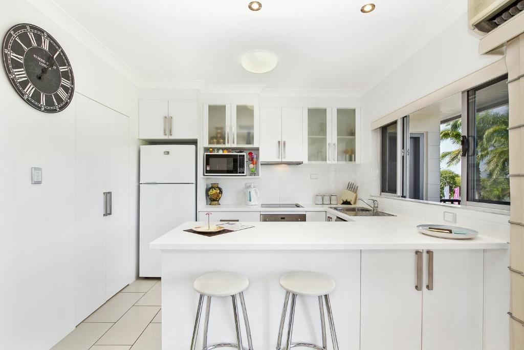 una cocina con armarios blancos y un reloj grande en la pared en EXECUTIVE PROPERTIES IN NORTH WARD TOWNSVILLE and ON MAGNETIC ISLAND en Townsville