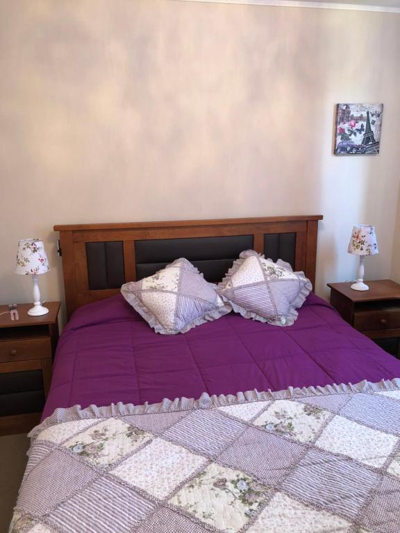 a bed with purple sheets and pillows on it at Departamento Libertad in La Serena