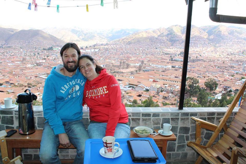 Ein Mann und eine Frau sitzen auf einem Tisch mit Aussicht. in der Unterkunft Wichana Wasi in Cusco