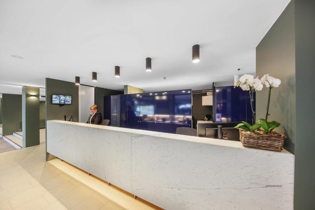 eine Person, die in einer Lobby mit einem Rezeptionsschalter steht in der Unterkunft Belconnen Way Hotel & Serviced Apartments in Canberra