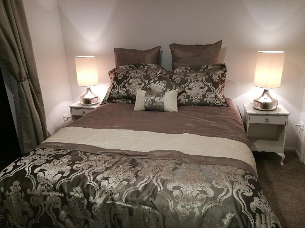 a bedroom with a large bed with two lamps at Terra Nostra in Mapua